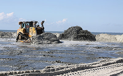 Bulldozer moving sand pumped onto the beach