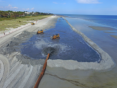 Bulldozers moving sand pumped onto the beach