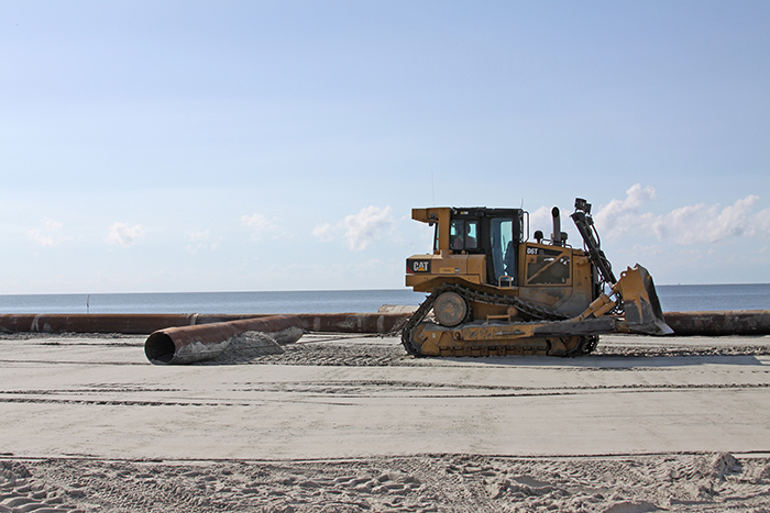 Tractor compacting newly placed sand