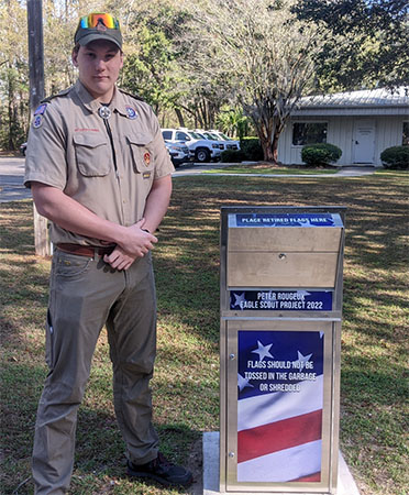 Peter Rougex standing next to Flag Retirement Box at HQ