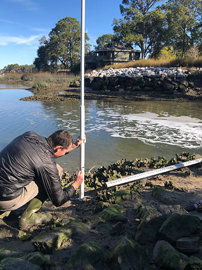 Man marking water levels on a sick in the marsh