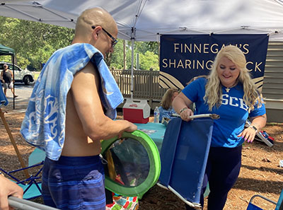 Bethany McDonald, founder of Finnegan’s Sharing Shack,  helps visitor John Yeh of Cleveland, GA pick out a beach chair at Driessen Beach Park